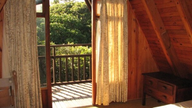 Une pièce en bois avec un balcon, un lit et une petite table.