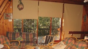 L’intérieur chaleureux d’un chalet, avec un plancher en bois, des meubles à motifs écossais et de grandes fenêtres donnant sur le paysage extérieur.