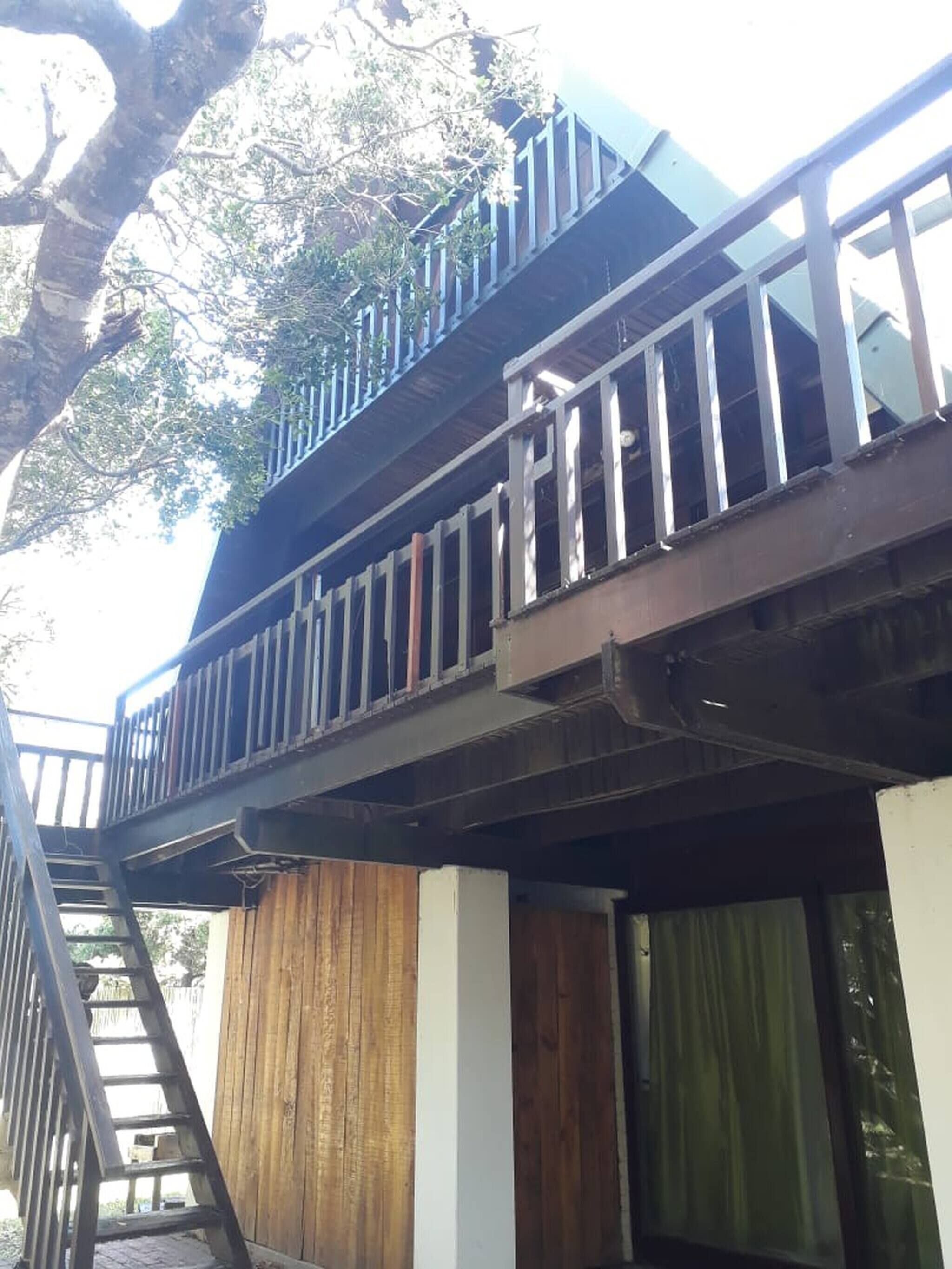 A multi-level wooden structure with a staircase and a balcony.