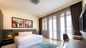 A modern hotel room with a large bed, a desk, and a TV. There are two framed pictures on the wall and a window with curtains. - Hutton Suites Hotel Managed By The Ascott Limited (George Town)