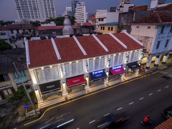 A hotel with a red tiled roof, multiple signage for 'Hutton Central' and 'Six Wine', and a street view with vehicles.