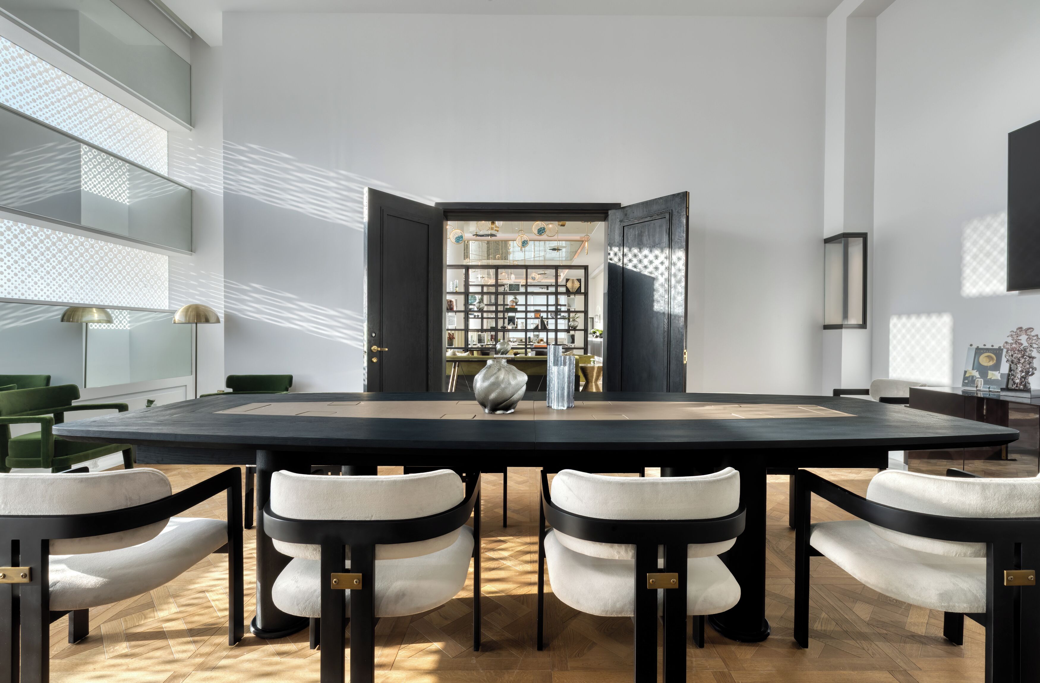 A modern dining room with a large table, four chairs, and a decorative vase.