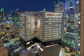 A modern building with a unique angular design, featuring a rooftop terrace and a parking area with multiple cars. -  Atheel KAFD Hotel (Riyadh)