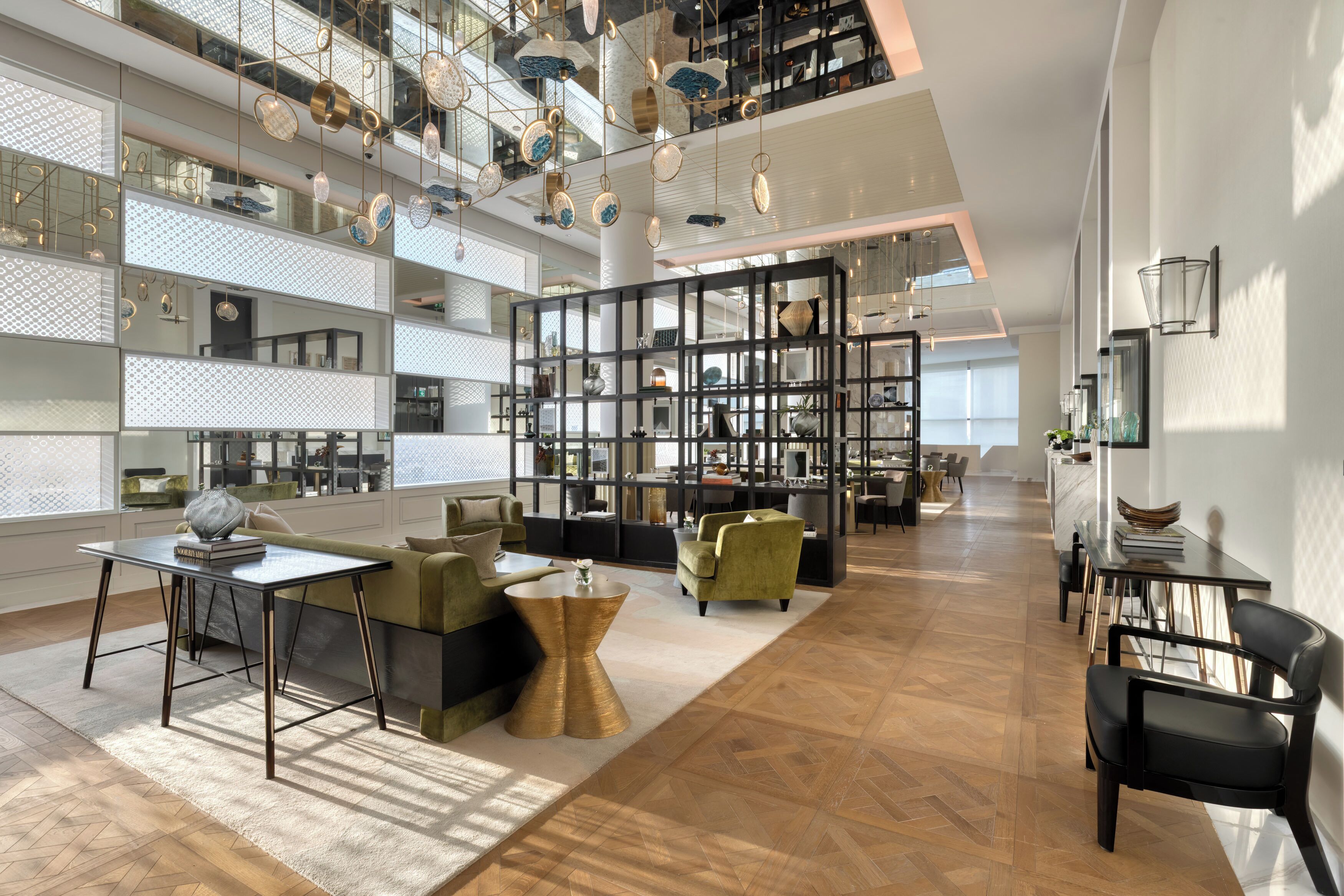 Un interior amplio con techo alto, una zona de estar central con una mesa de centro y una gran estantería llena de objetos variados.