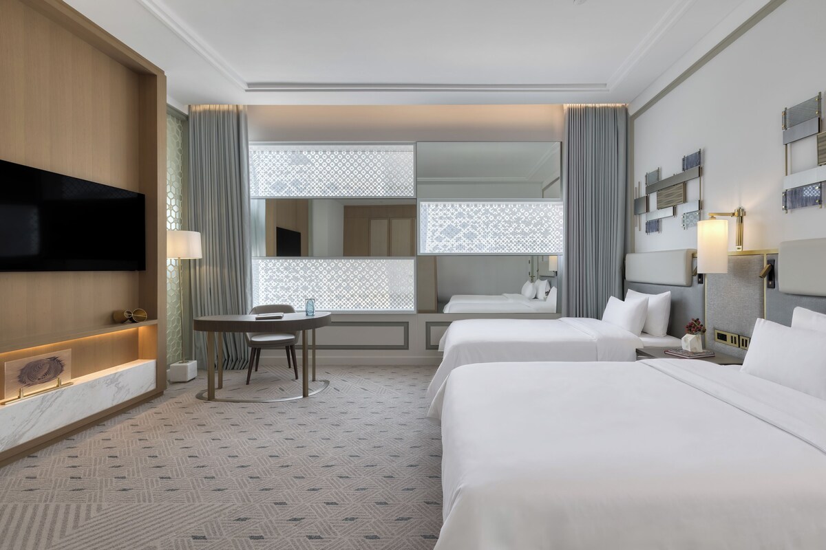 Habitación de hotel con dos camas, un escritorio y una televisión.