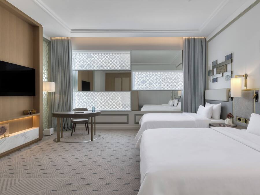 Une chambre d’hôtel avec deux lits, un bureau et une télévision.