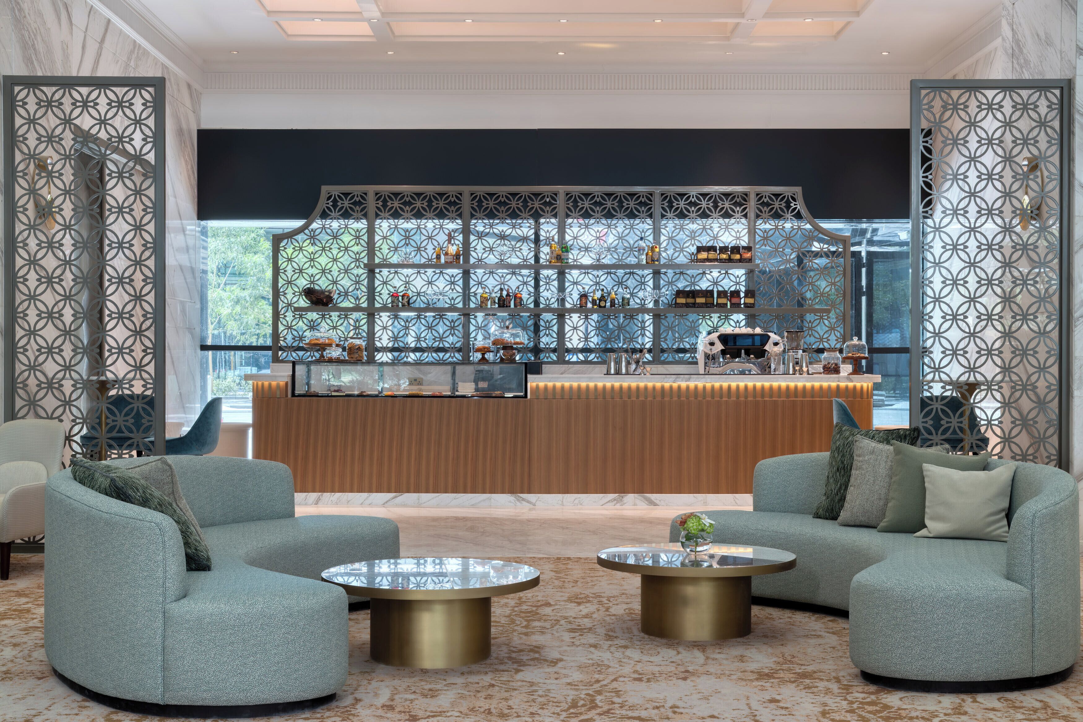 A modern lounge area with two sofas, a coffee table, and a bar area with shelves of bottles and glasses.