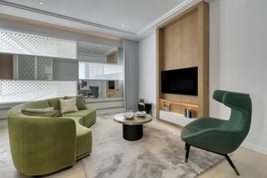 Un salon moderne comprenant un canapé, un fauteuil, une table basse et un téléviseur fixé à un mur en bois.