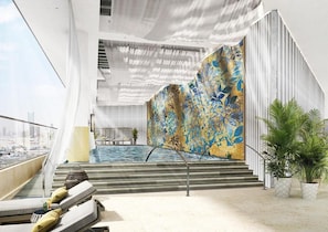 A modern indoor pool area with a view of the city, a staircase leading to a higher level, and a patterned wall. -  Atheel KAFD Hotel (Riyadh)