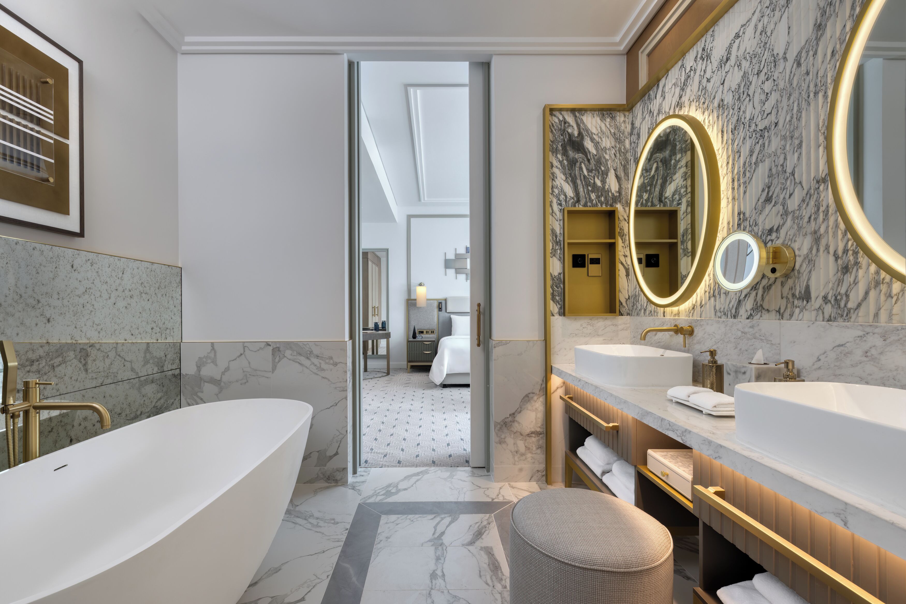 A modern bathroom with a freestanding bathtub, dual sinks, and a large mirror with a gold frame.