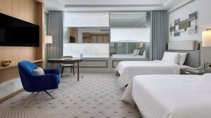Una habitación de hotel con televisión, dos camas, un escritorio y una silla.