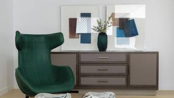 A green chair, a cabinet with drawers, and a vase with a plant on a table.
