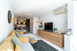Un salon moderne avec un canapé, un téléviseur et des meubles en bois.
