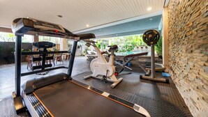 A gym with a treadmill, stationary bike, and weight bench.