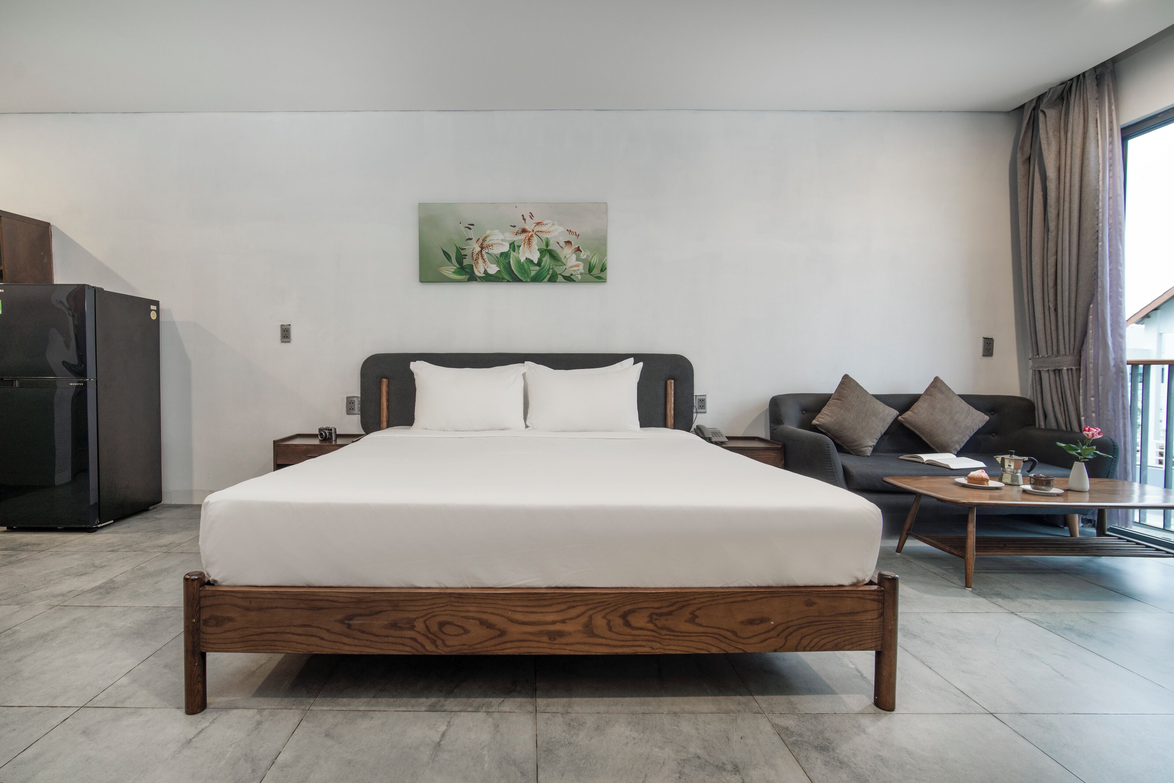 Una habitación de hotel moderna con una cama grande, un sofá, una mesita de centro y un cuadro en la pared.