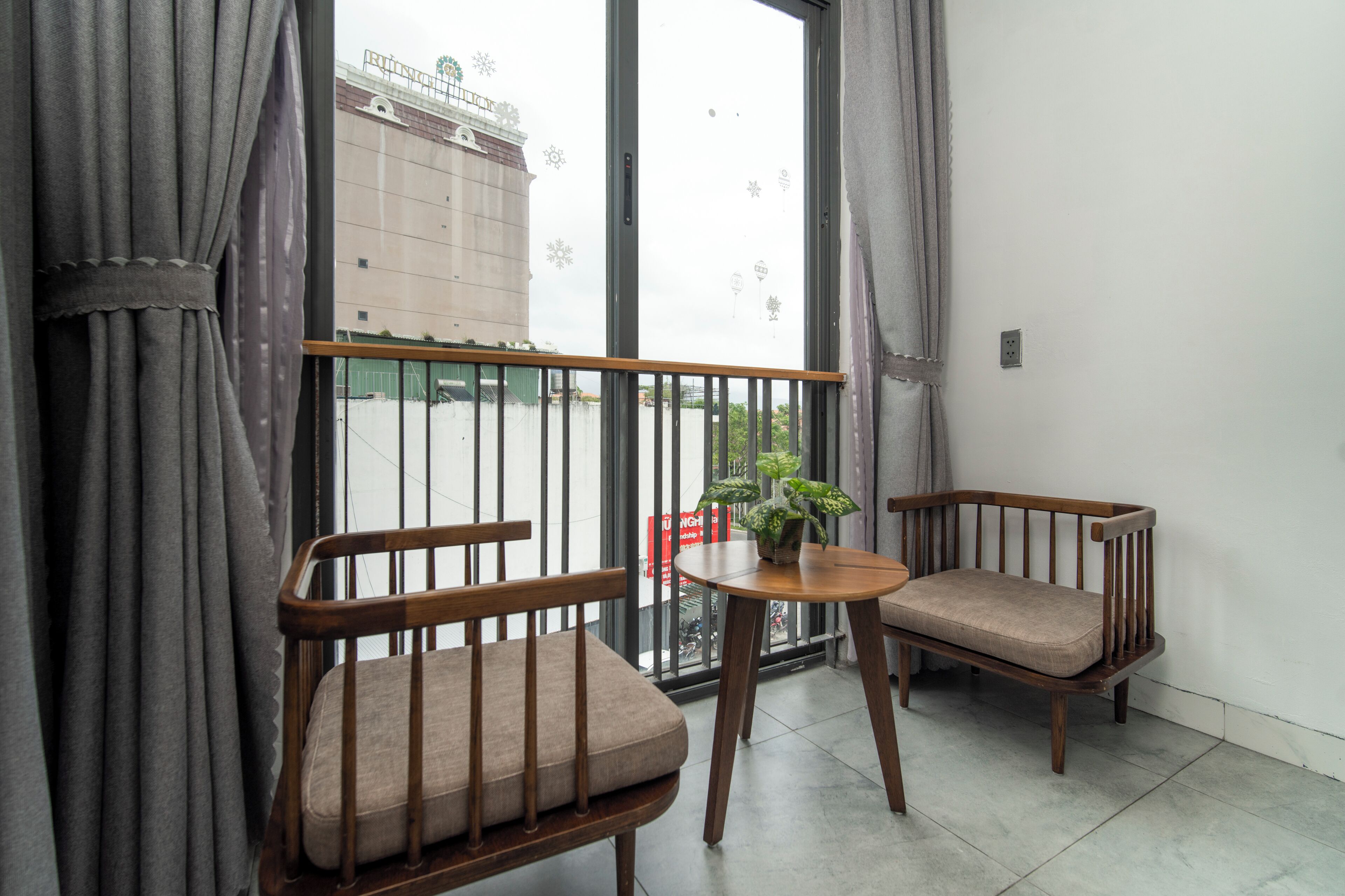 A balcony with two wooden chairs, a small round table, and a potted plant.