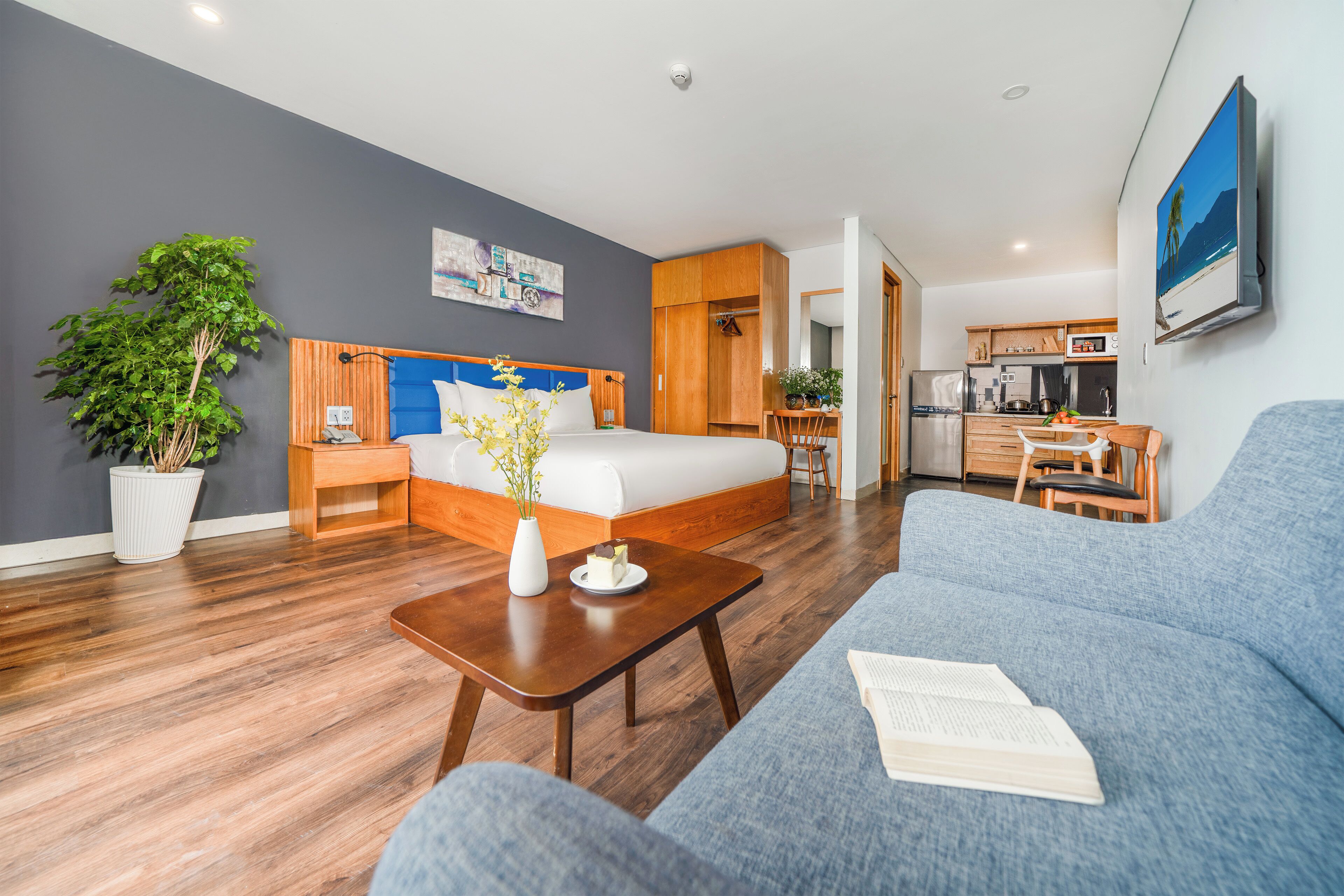 Een moderne hotelkamer met een bed, een bank, een eethoek en een keuken.