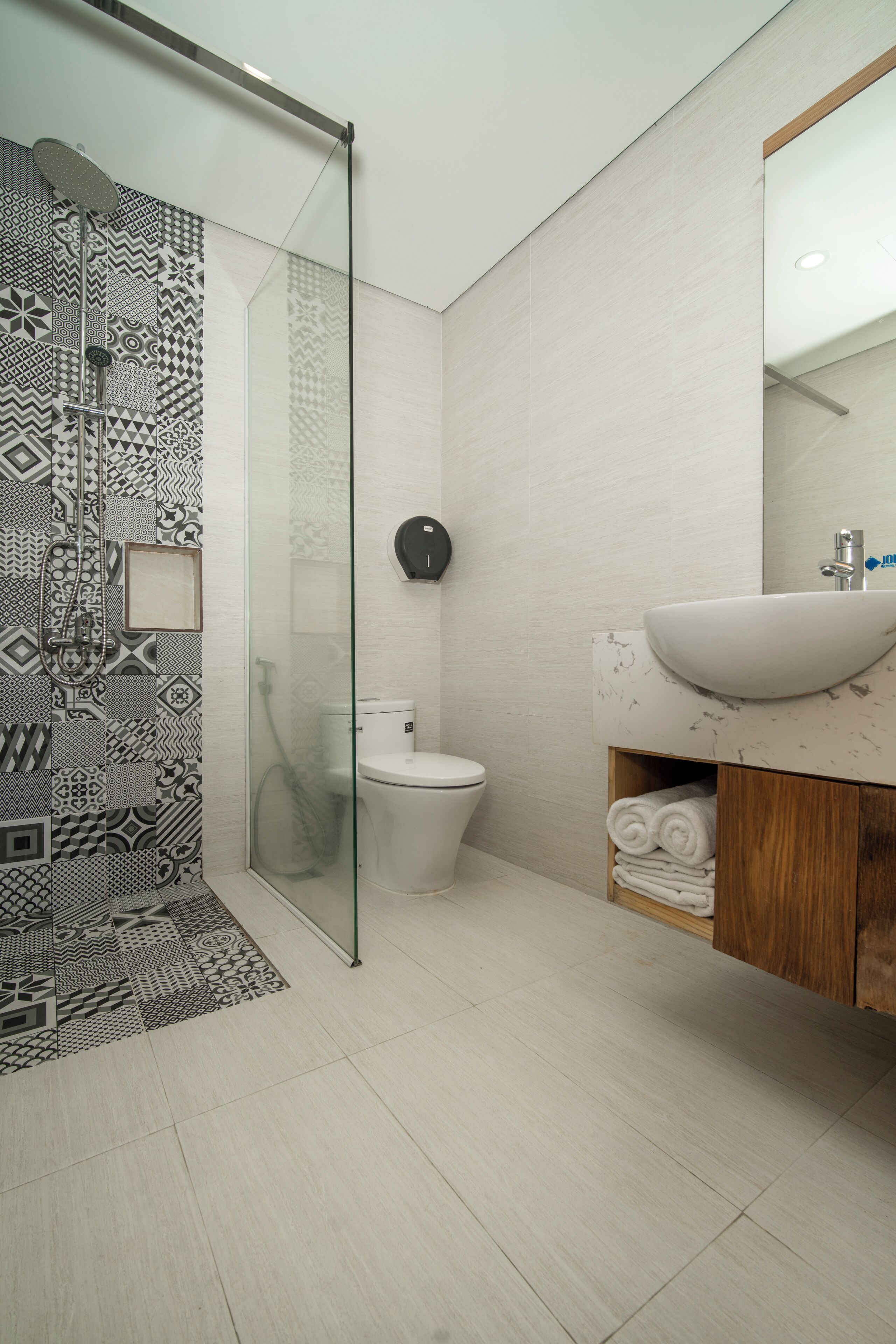 A modern bathroom with a patterned shower wall, a toilet, and a sink with a marble countertop.