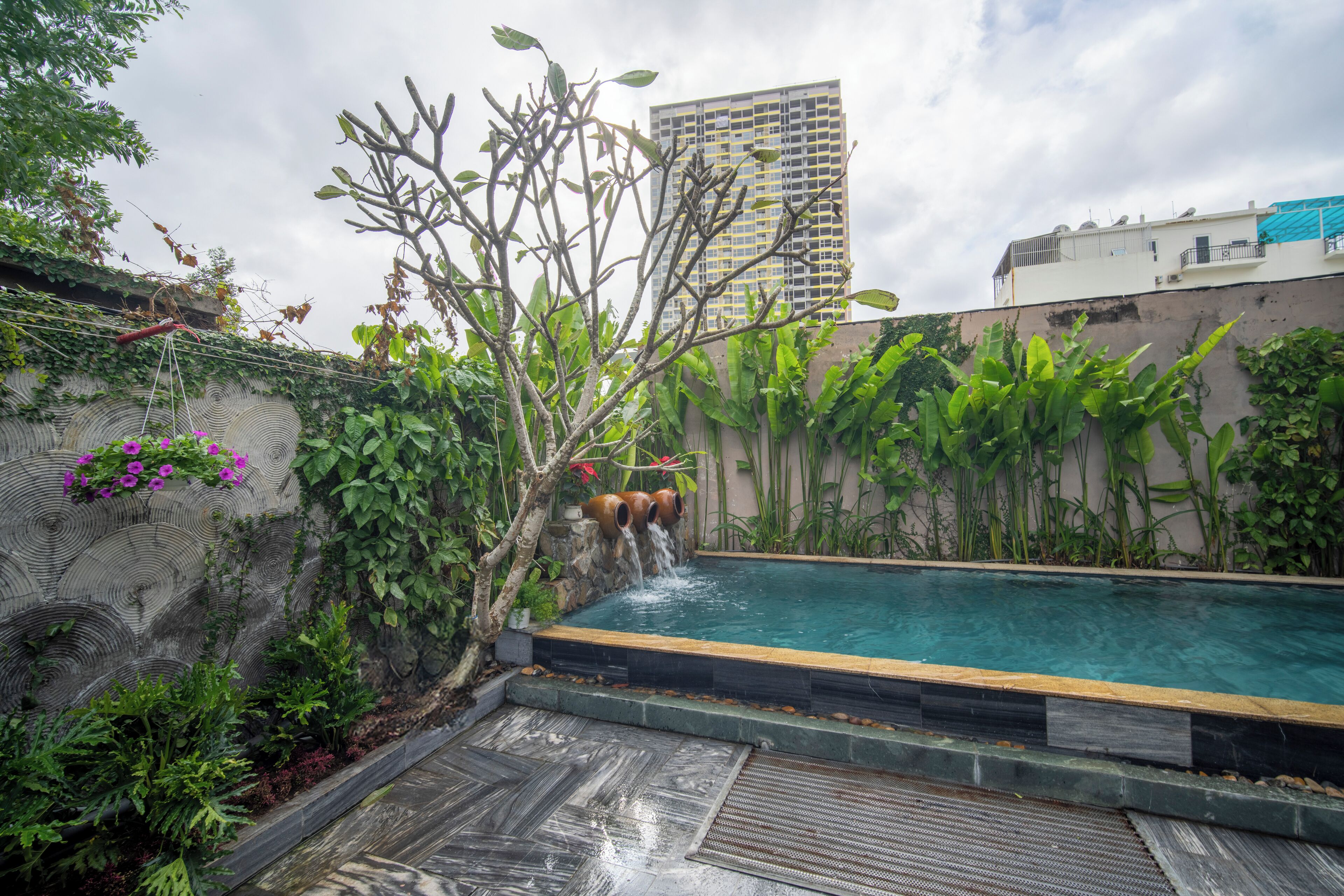 A swimming pool with a stone wall and tropical plants.