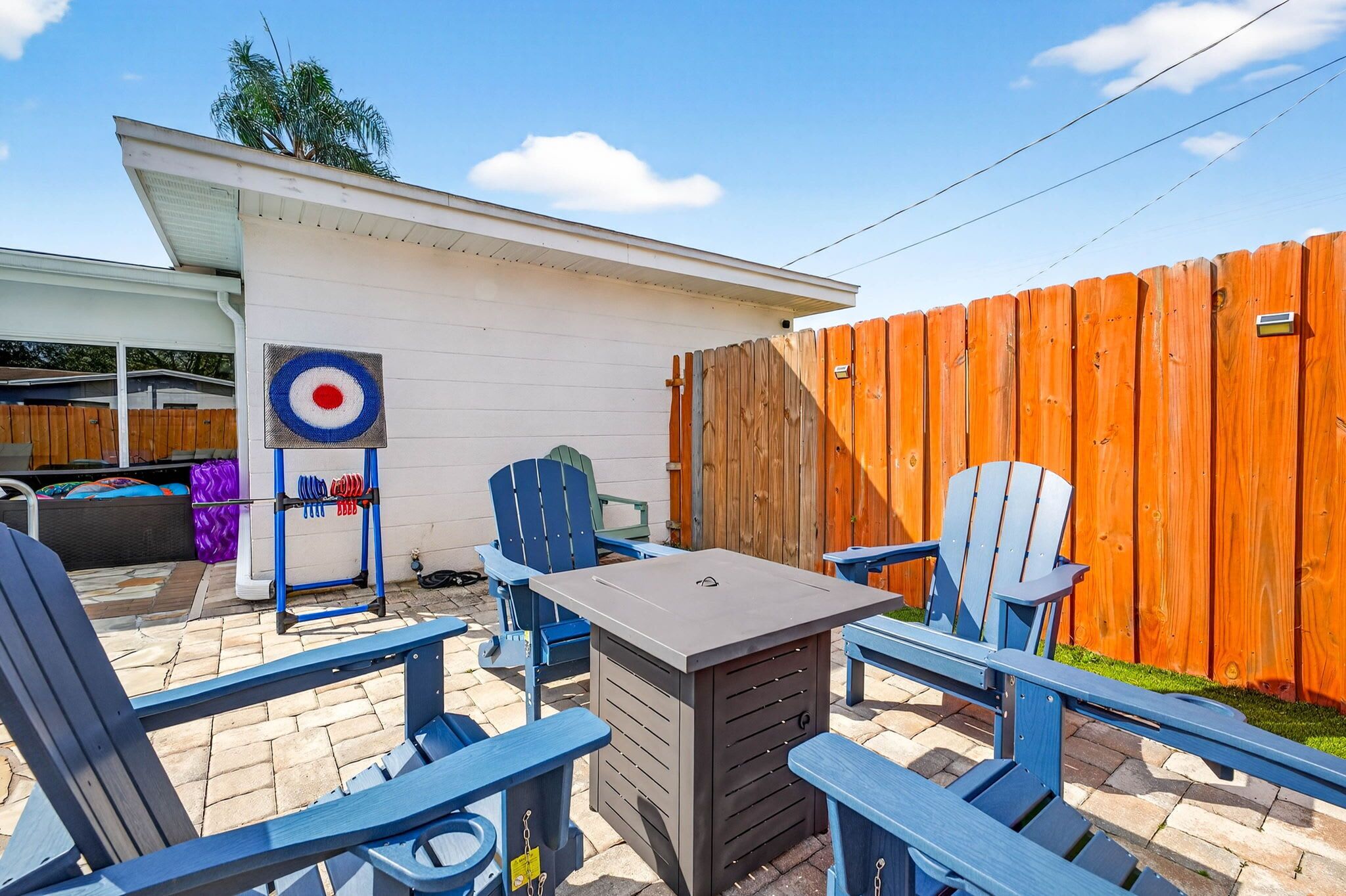 A backyard patio with a table and chairs, a target decoration, and a wooden fence.