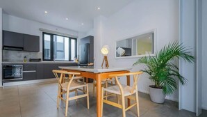 A modern kitchen with grey cabinets, a white countertop, and a dining area with a wooden table and chairs. - w*| Sublime 2BR w/ Rooftop In Casco Antiguo (Panamá)