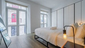 A modern bedroom with a bed, bedside lamp, and large windows. - w*| Sublime 2BR w/ Rooftop In Casco Antiguo (Panamá)