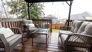 Una terraza cubierta al aire libre con mobiliario de mimbre y una mesa.