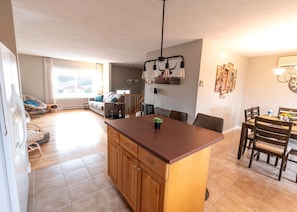 Una cocina amplia con una isla central, armarios de madera y un comedor con sillas y mesa.