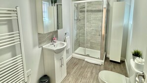 A modern bathroom with a shower, toilet, and sink.