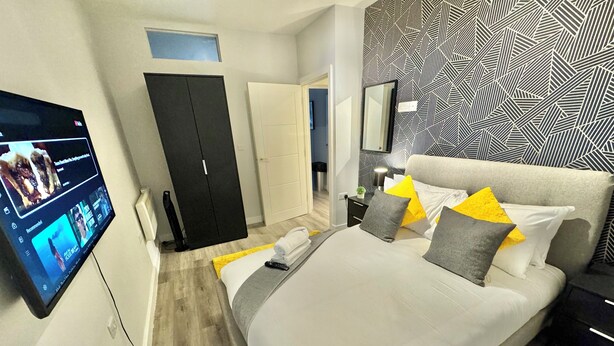 A modern bedroom with a bed, bedside table, and a TV mounted on the wall.