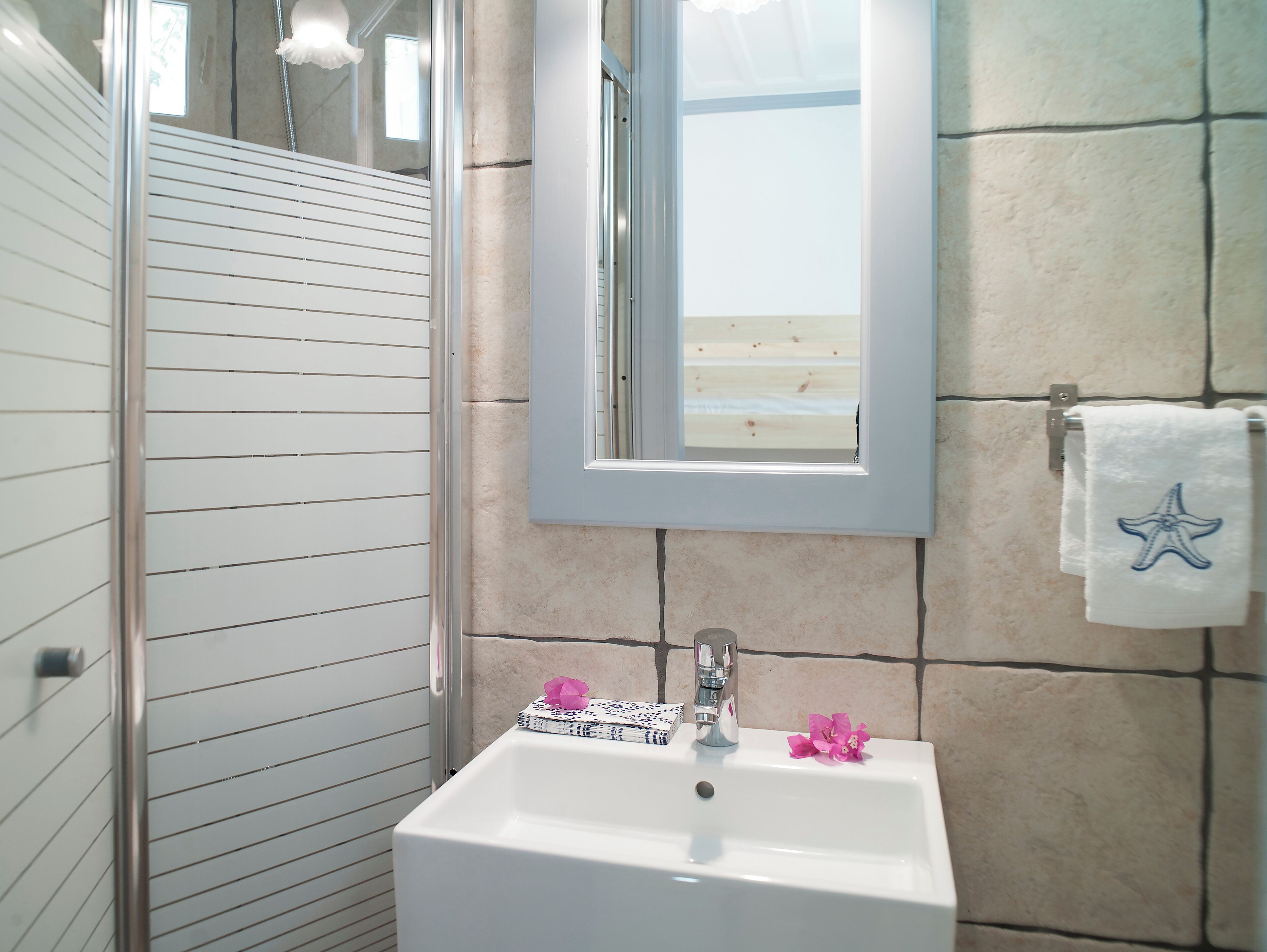 A bathroom with a white sink, a mirror, and a window.