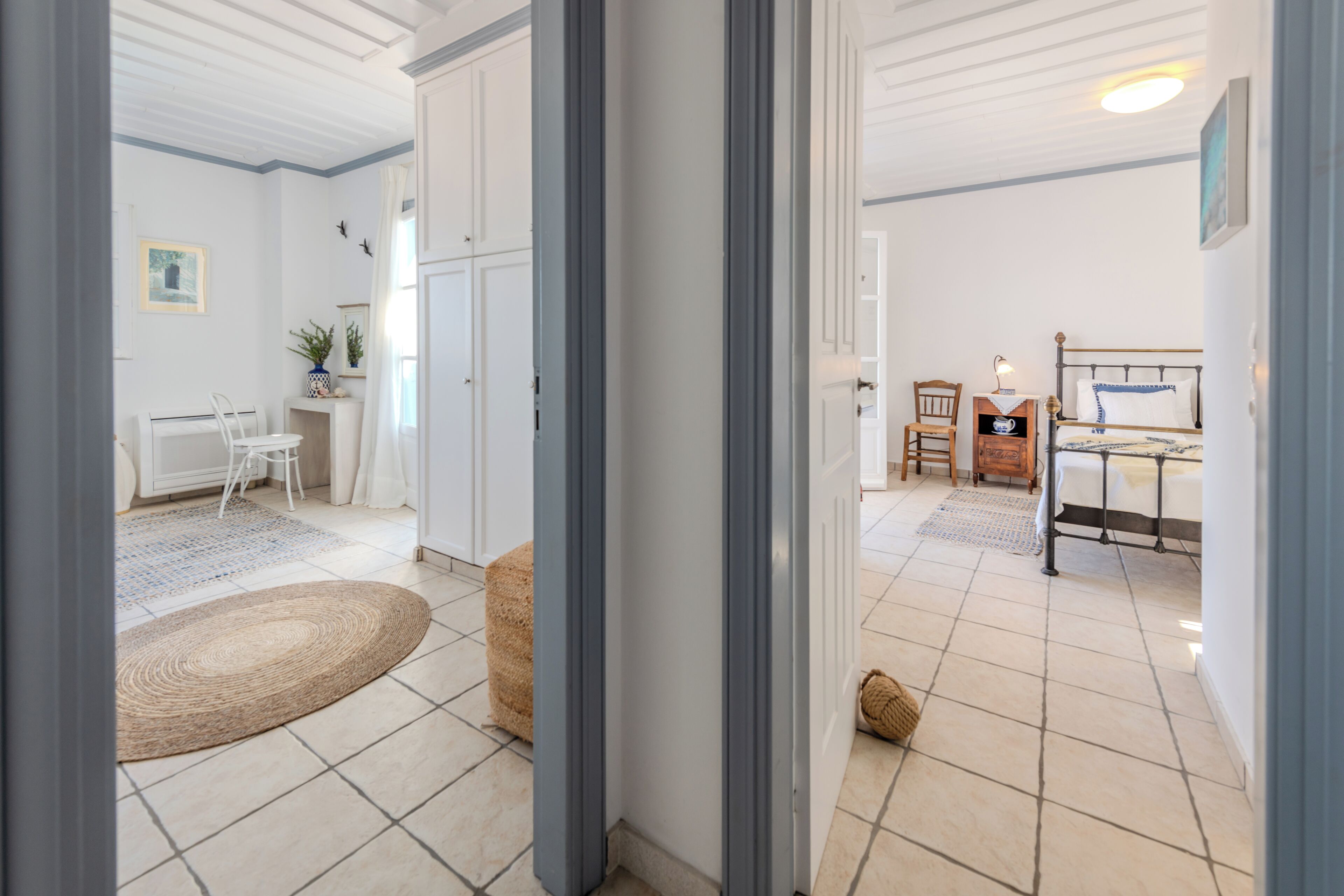 A room with a bed, a desk, and a chair. There is a window and a door.