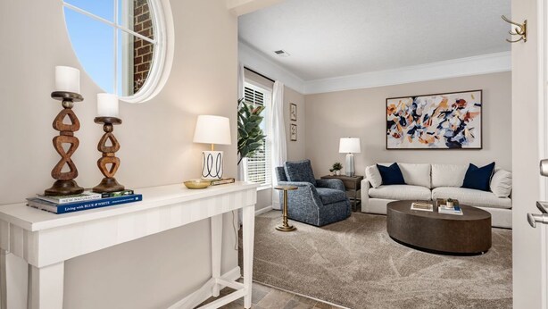 A living room with a white console table, two lamps, a blue armchair, a round coffee table, and a sofa with blue and white cushions. - New Albany 2BR | 2-Car Garage | Walk to Dinner (Columbus)