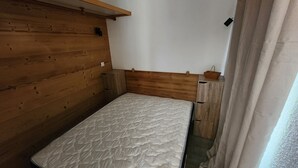 A small, wooden-framed room with a single bed, a wooden headboard, and a small wooden cabinet. - Center Val Thorens apartment 4 people (Les Belleville)