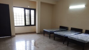 Quarto com quatro camas, janela com grades e luminária na parede.