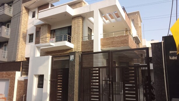 Uma casa moderna de dois andares com portão fechado, varanda e placa de 'ALUGA-SE' visível.