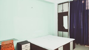 Quarto com cama, escrivaninha, cadeira e guarda-roupa.