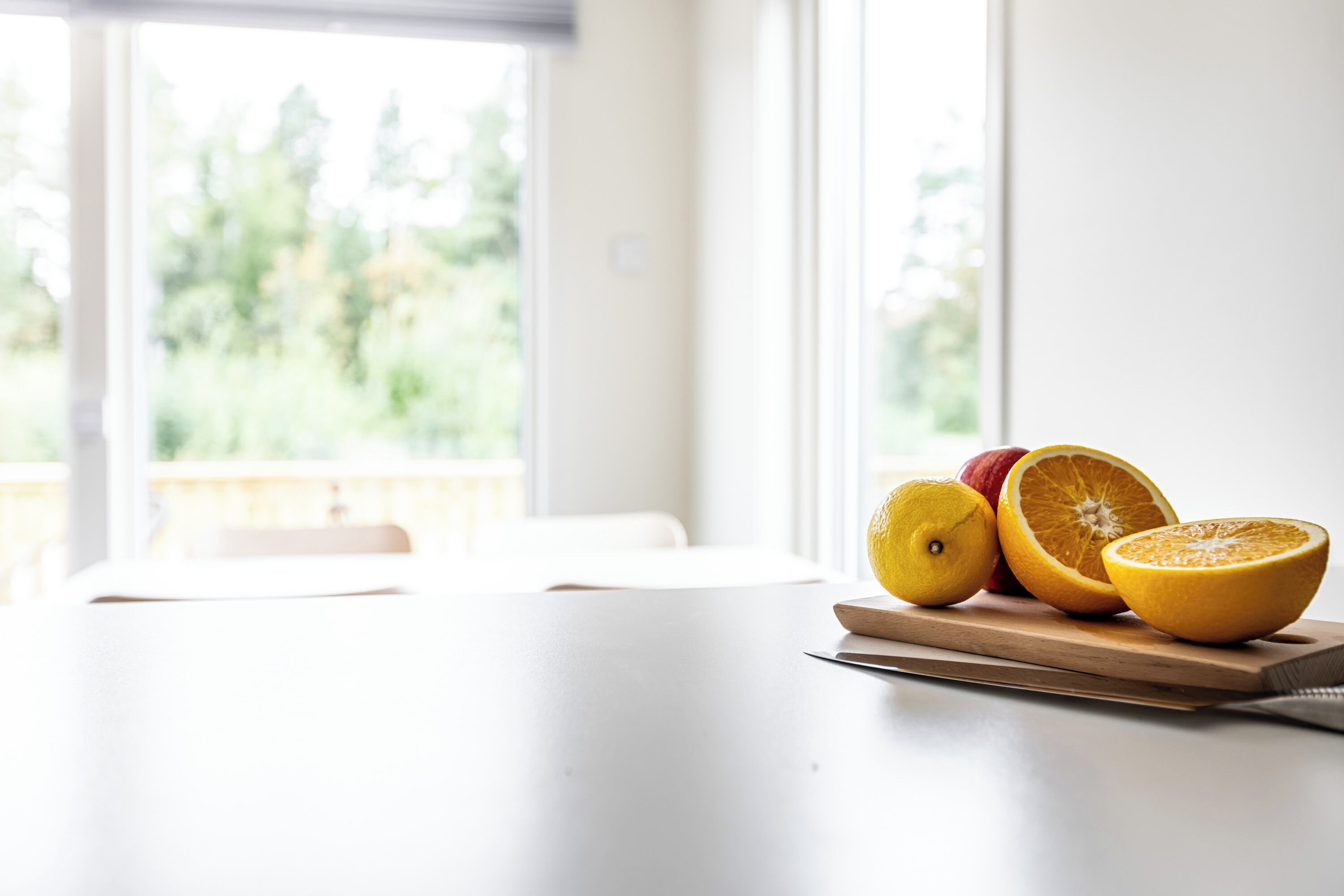 Eine Tafel mit Schneidebrett, auf dem ein Zitrone, eine halbe Orange und eine ganze Orange liegen.