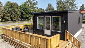 A compact, modern building with a wooden deck and a small outdoor seating area. - Private Chalet (Skelleftea)