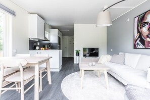 Un salon moderne avec un canapé blanc, une table à manger avec des chaises, une table basse et un téléviseur.