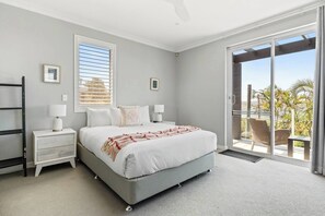 A bedroom with a large bed, a nightstand, a dresser, and a sliding glass door leading to a balcony. - Seabreeze - Balgowlah Heights Beach House w/ Pool (Balgowlah Heights)