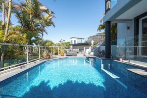 A clear blue pool with a modern design, surrounded by palm trees and a glass railing. - Seabreeze - Balgowlah Heights Beach House w/ Pool (Balgowlah Heights)