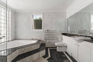 A modern bathroom with a bathtub, toilet, and sink. - Seabreeze - Balgowlah Heights Beach House w/ Pool (Balgowlah Heights)