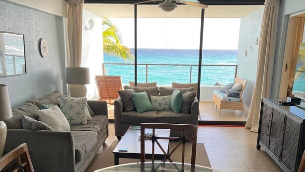 Ein Wohnzimmer mit Meerblick, ausgestattet mit einer Couch, Sesseln und einem Esstisch.
