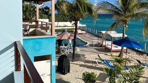 Ein Balkon mit Pool, Liegestühlen, Sonnenschirmen und Topfpflanzen.