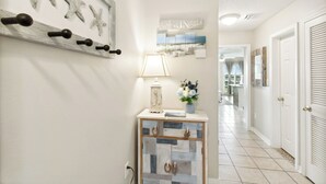 Een hal met een console tafel, decoratieve zeester decoratie aan de muur, een lamp en een vaas met bloemen.