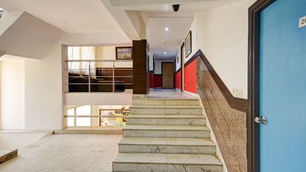 A staircase leading to a second floor with a blue door on the right. - Mauryan Stay, Yashobhoomi (New Delhi)