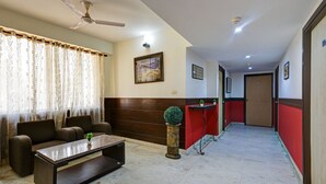 A hotel lobby with a sofa set, a coffee table, a reception desk, and a corridor leading to a door. - Mauryan Stay, Yashobhoomi (New Delhi)