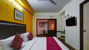 A hotel room with a bed, a TV, and a door. - Mauryan Stay, Yashobhoomi (New Delhi)