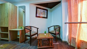A room with a wooden desk, two chairs, a small table with a plant, a framed picture on the wall, and a wooden wardrobe. - Mauryan Stay, Yashobhoomi (New Delhi)